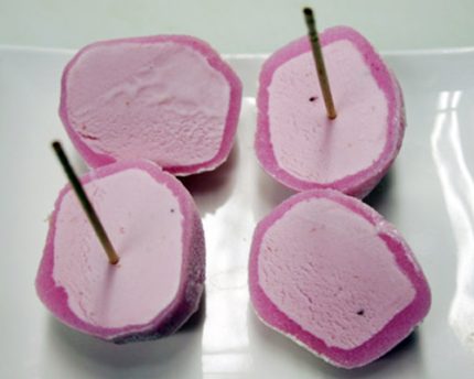 Small round dessert ball of ice cream wrapped in a rice cake covering strawberry, vanilla, kona coffee, green tea, mango